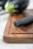 Close-up of a knife handle with a logo on a wooden cutting board, with eggplants in the background. Voir les images du produit