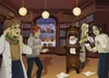 Four young women are gathered around a grandfather clock with a picture of Santa Claus inside, in a library decorated for Christmas. Produktbild-Vorschau