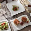 A table setting with plates of food, cutlery, and a glass of drink. Náhled obrázku produktu