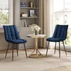 Two blue upholstered chairs flank a small round table with a vase of white flowers, set in a room with a bookshelf and window. Produktbild-Vorschau