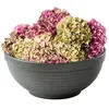 A dark gray bowl filled with dried hydrangeas in shades of pink and green. Produktbild-Vorschau