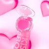 A close-up of a pink lip gloss with its lid open, set against a pink background with heart shapes. Anteprima dell’immagine prodotto