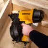 A hand using a yellow nail gun to fasten wooden beams together. Produktbild-Vorschau