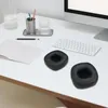 A desk setup with a computer monitor, keyboard, notebook, pens, and two black ear pads. Produktbild-Vorschau
