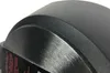 A close-up view of the rim and side of a black frying pan, showing textured and brushed metal finishes. A black label with red text is partially visible along the bottom edge. Anteprima dell’immagine prodotto