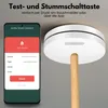 A smart smoke detector is shown mounted on a ceiling, with a smartphone displaying an app interface next to it. A wooden pole extends from the smoke detector. Produktbild-Vorschau