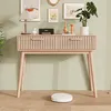 A console table with two drawers, decorated with a lamp, a speaker, and plants, in a room with a green wall and wooden floor. A robot vacuum cleaner is on the floor. Produktbild-Vorschau