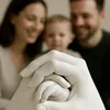 A close-up of a family's hands, including a baby's hand, forming a sculpture. The parents are blurred in the background. Náhled obrázku produktu