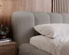 A close-up view of a bed with a textured headboard and pillows. Náhled obrázku produktu