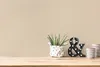 A decorative ampersand sign and a potted plant sit on a wooden surface against a plain beige wall. Produktbild-Vorschau