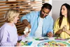 Three people playing a board game at a table. Produktbild-Vorschau