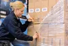 A person is cutting plastic wrap off a stack of boxes. Produktbild-Vorschau