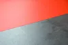 A close-up, angled view of a red surface meeting a textured gray surface. Produktbild-Vorschau