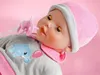 Close-up of a baby doll wearing a hat and pajamas, with a pacifier in its mouth. Náhľad obrázku produktu