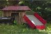 Toy farm vehicles and a shed in a grassy outdoor setting. Produktbild-Vorschau