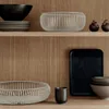 A display of decorative bowls and trays on wooden shelves. Produktbild-Vorschau