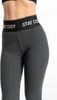 A close-up shot of a person wearing grey leggings with a black waistband that says 'STAY COSY'. Produktbild-Vorschau