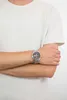 A person wearing a white t-shirt and a silver watch on their left wrist. Produktbild-Vorschau