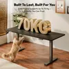 A cat is playing under a standing desk with large gold letters spelling '70KG' on it. Produktbild-Vorschau
