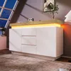 A modern white sideboard with integrated orange lighting, set in a room with a large angled window. Voir les images du produit
