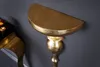 A close-up view of a gold-colored wall console shelf mounted on a dark gray wall. Produktbild-Vorschau