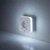 A white LED night light with a power outlet and two USB ports, plugged into a wall. Voir les images du produit