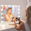 A woman is applying makeup in front of a lighted vanity mirror. Produktbild-Vorschau