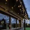 Icicle lights are draped along the eaves of a wooden building, illuminating the exterior. Podgląd zdjęcia produktu