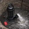 A submersible pump is operating in a concrete well, pumping water out. Podgląd zdjęcia produktu