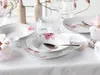 A table setting with floral-patterned porcelain plates and bowls, complete with cutlery and glasses. Náhľad obrázku produktu