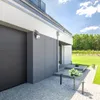 A modern house with a garage, driveway, and garden. Podgląd zdjęcia produktu