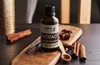 A bottle of vanilla extract is placed on a wooden board, surrounded by cinnamon sticks, a vanilla bean, and star anise. Náhled obrázku produktu
