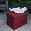 A person's feet in socks resting on a red ottoman in a living room setting. Náhled obrázku produktu
