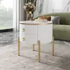 A round white side table with gold legs and drawer pulls, placed in a living room setting next to a green sofa. Anteprima dell’immagine prodotto