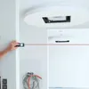 A person is using a laser distance measurer to measure a wall in a room that appears to be under construction or renovation. Voir les images du produit