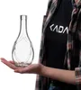 A person's hand is holding a clear glass bottle with decorative elements. The person is wearing a plaid shirt and a black t-shirt with white text. Anteprima dell’immagine prodotto