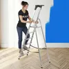 A woman is using a step ladder to paint a wall blue. Podgląd zdjęcia produktu