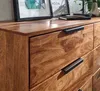 A close-up view of a wooden dresser with black handles, showing the texture of the wood and the drawers. Produktbild-Vorschau