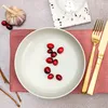 A top-down view of a table setting with a plate of cranberries, a garlic bulb, and cutlery. Náhled obrázku produktu