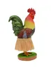 A decorative wackelfigur (bobblehead) of a rooster wearing a grass skirt, standing on a green base. Produktbild-Vorschau
