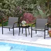 A patio furniture set with two chairs and a table next to a swimming pool, with lush greenery and flowers in the background. Podgląd zdjęcia produktu