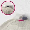 A close-up view of a white cap holder mounted on a wall, with a blue cap being placed into it. An inset circle shows a similar view. Produktbild-Vorschau