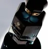 A close-up shot of a dark blue perfume bottle with gold accents. Voir les images du produit