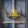 A festive Christmas wreath with lights and ornaments hanging on a window with a snowy background. Anteprima dell’immagine prodotto