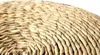 A close-up view of the woven texture of a round, beige object, likely a table or basket. Produktbild-Vorschau