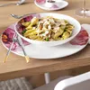 A table setting with a bowl of pasta and a floral-patterned plate. Voir les images du produit