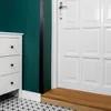 A white dresser next to a green wall and a white door with a wooden step. Anteprima dell’immagine prodotto