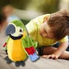 A child is playing with a stuffed parrot toy outdoors. Anteprima dell’immagine prodotto