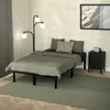 A bedroom scene with a bed, nightstand, lamp, and artwork. Podgląd zdjęcia produktu