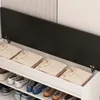 A shoe cabinet with a lift-up seat, showing folded sweaters inside the storage compartment and shoes on the shelves below. Podgląd zdjęcia produktu